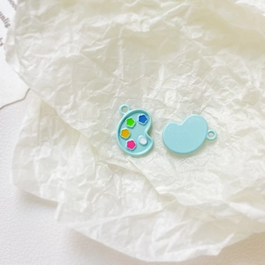 Macro shot of light blue palette alloy charms with colorful paint drops for DIY jewelry