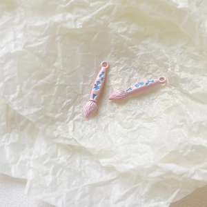 Detailed macro of pink enamel paintbrush charms with floral patterns for jewelry DIY