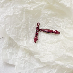 Macro shot of red enamel paintbrush pendants with cartoon silhouettes for jewelry DIY