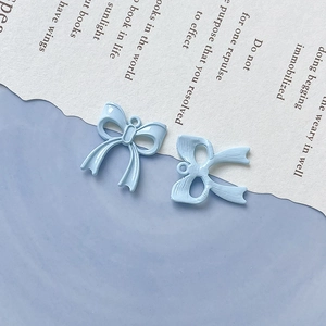 Dettaglio di ciondoli a fiocco in smalto azzurro con ganci per creazione gioielli DIY