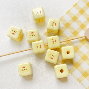 Dettaglio macro di perline a cubo giallo crema con motivi a orso per creazione gioielli DIY