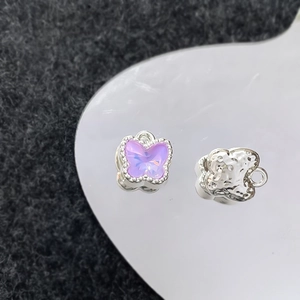 Macro-opname van vlinderhangers met paars kristal en zilveren metalen bedeltjes op een dienblad