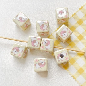 Dettaglio macro di perle a forma di orso a quadretti giallo crema per gioielli DIY