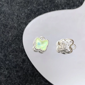 Detail van zilveren vlinderbedels met lichtgroene stenen voor DIY-sieraden maken