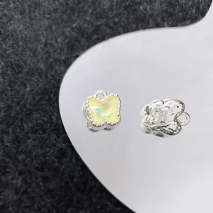 Detailweergave van zilveren vlinderhangers met gele kristallen en gehamerde textuur