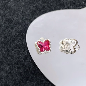 Macrodetail van vlinderhanger met rood kristal en zilveren gehamerde achterkant