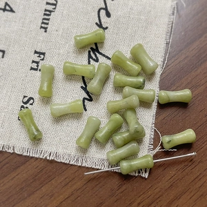 Dettaglio macro di perline in pietra naturale verde chiaro a forma di osso per gioielli