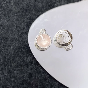 Detail van ronde hanger met roze gefacetteerde edelsteen en gehamerde metalen achterkant