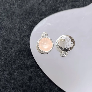 Macro-opname van zilveren gehamerde bedels en roze edelsteenhanger op een wit dienblad