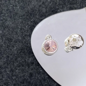 Detail van roze kristallen hanger en zilveren gehamerde bedel met een zirkoniasteen