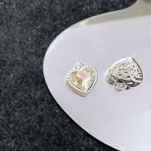 Macro-opname van hartvormige bedel met iriserende steen en milgrain detail op metaal