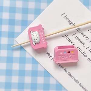Close-up of pink toy toaster resin charms with TOAST lettering for DIY jewelry crafts