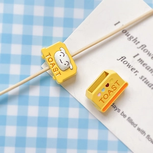 Detail of yellow toast shaped alloy bead featuring a cute character and TOAST engraving