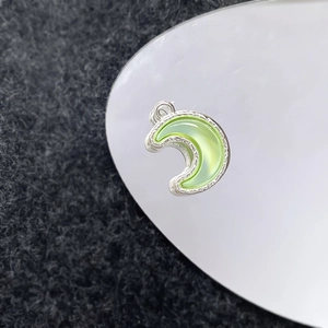 Macro-opname van een maanvormige zilveren hanger met lichtgroene edelsteen inleg
