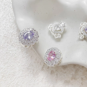 Detailed view of silver-plated heart and carriage beads with purple and pink gemstones