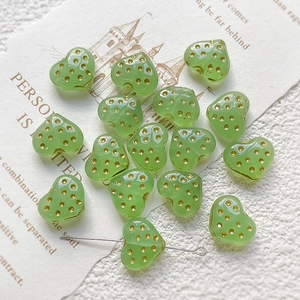 Detail of strawberry green heart glass beads with gold dots for DIY jewelry making