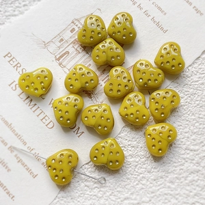 Macro shot of yellow heart glass beads with dot patterns for DIY jewelry making