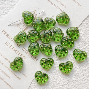 Close-up of translucent heart-shaped glass beads with gold dots for DIY jewelry making