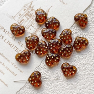 Detailed view of amber glass heart bead with gold polka dots and threading hole