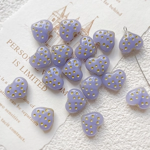 Detail of purple heart-shaped glass beads with gold polka dots for DIY jewelry making