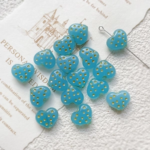 Macro detail of sky blue heart glass beads with gold dots for DIY jewelry making