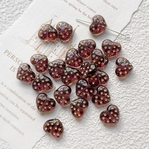 Macro shot of translucent heart-shaped glass bead with golden dots for DIY jewelry making