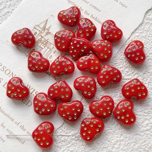Macro detail of red heart glass beads with gold dots for DIY jewelry making and crafts