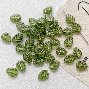 Vue détaillée de perles feuilles en verre vert avec veines dorées pour bijoux DIY créatifs