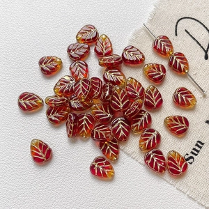 Détail macro de perles feuilles en verre dégradé rouge et jaune avec veines dorées pour bijoux