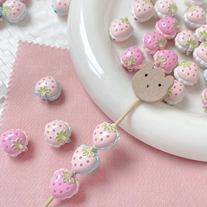 Detalle de cuentas de fresa rosa para joyería artesanal en plato de cerámica blanco