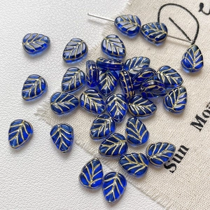 Détails de perles de verre bleues en forme de feuilles avec nervures dorées pour bijoux