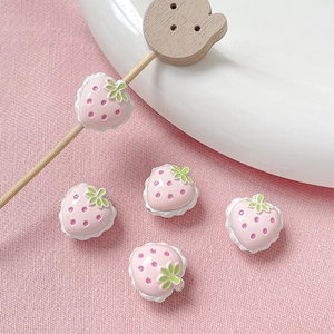 Detalle de dijes de fresa de resina rosa con hojas verdes para joyería artesanal