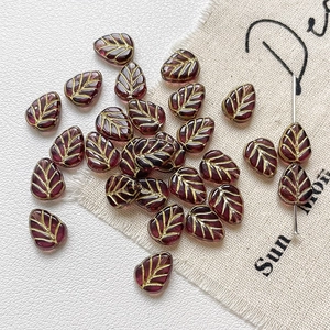 Détail de perles en verre en forme de feuille avec veines dorées et fini rouge foncé