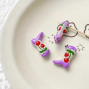 Detail of boot-shaped purple and white acrylic bead with hand-painted cherry pattern