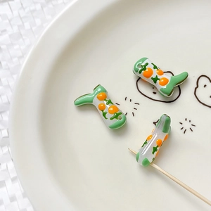 Macro detail of boot-shaped glass beads with hand-painted orange patterns for DIY jewelry