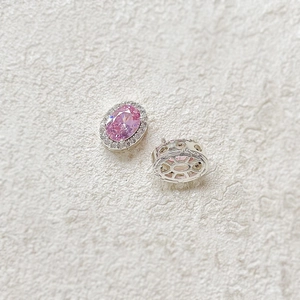 Macro detail of 18k gold plated pink halo oval gemstone pendant with white side stones