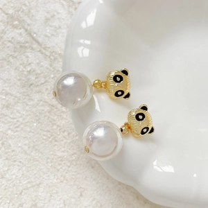 Süße 18k vergoldete Panda-Ohrstecker mit großen weißen Perlen auf einem Keramikteller