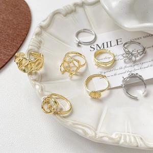 Assortimento di anelli a fiore irregolare placcati oro 18k e argento su piatto