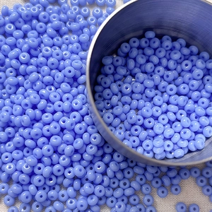 Macro shot of 4mm light blue glass seed beads on white fabric for DIY jewelry making