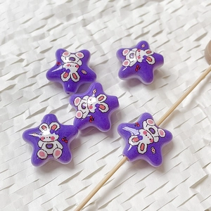 Dettaglio di perline acriliche viola a forma di stella con stampe di coniglio per fai da te