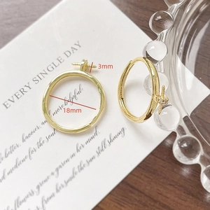 Dettaglio di orecchini a cerchio placcati oro 18k con croce e misura diametro di 18mm