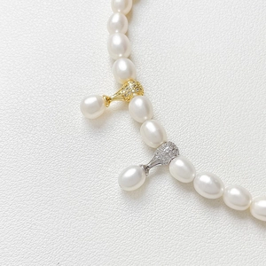 Détail d'un collier de perles plaqué or 18k avec des breloques serties de zircons brillants