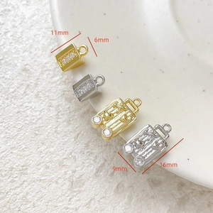 Macro shot of gold and silver mini suitcase pendants with zircon for DIY jewelry making