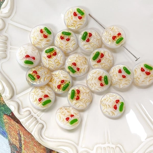 Macro shot of hand-painted cherry glass beads for DIY jewelry making in a white plate
