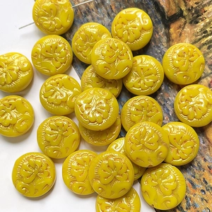 Macro detail of yellow peony floral engraved beads with a central hole for DIY jewelry making