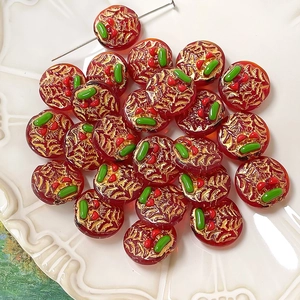 Macro shot of handmade dark red glass beads with gold foil and 3D floral accents
