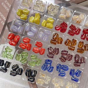 Detailed view of colorful glass tulip beads with gold lines in a clear storage box