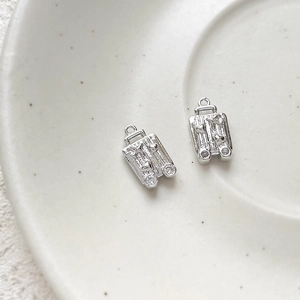 Macro shot of silver mini suitcase charms with heart pattern and tiny zircon wheels