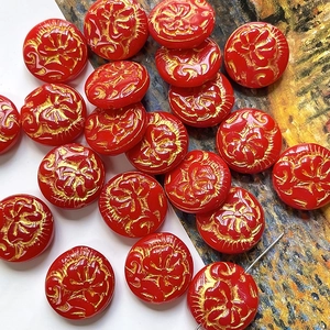 Macro shot of vintage red beads with gold peony floral relief for DIY jewelry making