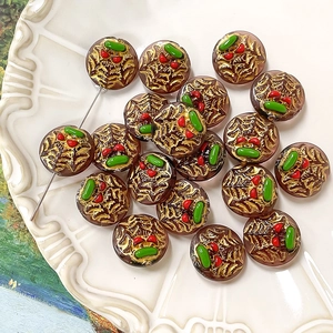 Macro detail of hand-painted cherry glass bead with gold texture for DIY jewelry